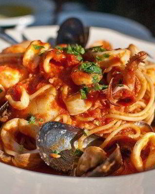 Паста с морепродуктами, зеленью и чесноком в томатном соусе